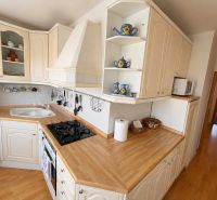 A stylish kitchen with white cabinets and a wood-patterned floor in a three-room apartment.
