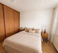 A bedroom with a wood-patterned floor, a bed, and a built-in wardrobe in a 3-room apartment.