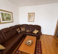 A corner leather sofa and a wooden decor floor in a 3-room apartment.