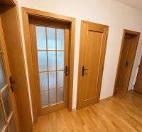Wooden doors with various patterns on the floor with wooden decor in a 3-room apartment.