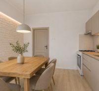 A kitchen in a 3-room apartment with a wooden table and a floor with a wooden decor.