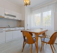 A kitchen in a 3-room apartment with a dining table and chairs, floor with wooden decor.