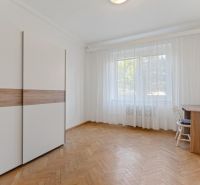 Spacious room with wood-patterned flooring, built-in wardrobe, and large window in a three-room apartment.