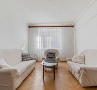 Living room with sofas, an armchair, and a wooden decor floor in a three-room apartment.