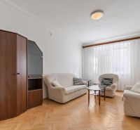 Living room with white sofas, a display cabinet, and a wooden decor floor in a three-room apartment.