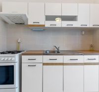 A kitchen in a 3-room apartment with white cabinets and a gas stove.