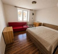 A bedroom with wooden decor, a bed, a red sofa, and a window in a family house.