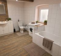 A bathroom in a family house with a washing machine, a bathtub, and a floor with a wooden decor.