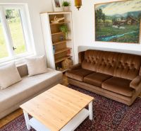 Living room in a family house with sofas, a table, and a painting on a floor with a wooden decor.