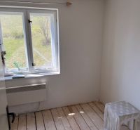 A white room in a family house with a wood-patterned floor and a view of the garden.