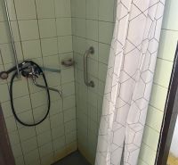A shower corner with tiles and a curtain in the bathroom of a family house.