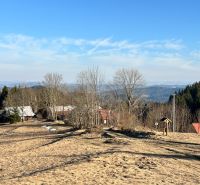 A view of family houses in Korňa surrounded by nature and forests, clear skies.