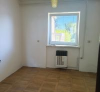 A room with a wooden floor, white walls, and a window in a family house.