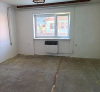 A room with one window, a light fixture, and a concrete floor in a family house.