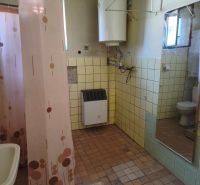 Bathroom with a gas heater in a family house, with a pink shower curtain and tiles.