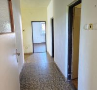 A hallway with light walls, tiles, and doors in a family house.