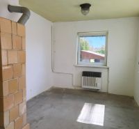 A room in a family house with a stove and a window, without floor decoration.