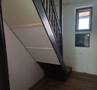 A staircase in a family house with a wooden decor floor and a small window.