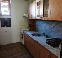 A kitchen in a family house with wooden cabinets and a floor with a wooden design.