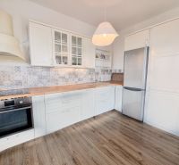 A kitchen in a 2-room apartment with tiled walls and a wooden decor floor.