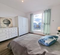Bedroom in a two-room apartment with a wood-decor floor and cozy furnishings.