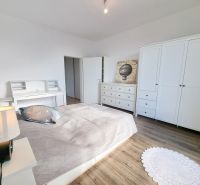 Bright bedroom with white furniture and a bed, 2-room apartment.