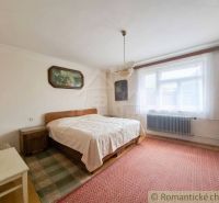 Bedroom in a family house with carpets, a bed, and a painting on the wall.