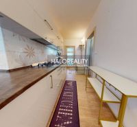 A kitchen with white cabinets and decorative tiles in a two-room apartment.