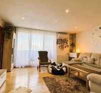 Living room with comfortable seating, large wall clock, and floor with wooden decor.