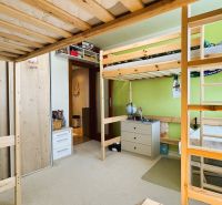 Children's room in a 3-room apartment with a wooden bunk bed and a green wall.