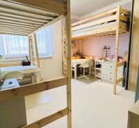 A room with bunk beds, desks, and carpeted flooring in a 3-room apartment.