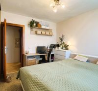 A bedroom in a 3-room apartment with a desk and decorative plants.