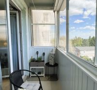 A glazed balcony in a 3-room apartment with seating and a view of nature.