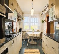 A kitchen in a 3-room apartment with dining, white cabinets, and appliances.
