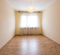 A room with a wooden decor floor and curtains in a 3-room apartment.