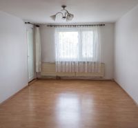 An empty room with a wooden floor and curtains in a 3-room apartment.