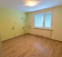 A room in a 3-room apartment with a wooden decor floor and wall stickers of plants.