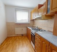 A kitchen in a 3-room apartment with a kitchen unit and a floor with a wooden decor.
