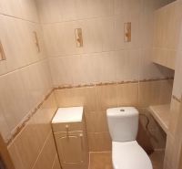 A toilet with beige tiles in a 3-room apartment.