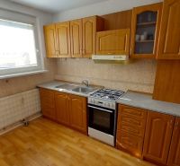 A kitchen with wooden cabinets and a wood-patterned floor in a 3-room apartment.