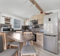 A kitchen in a cabin with wooden decor, a dining table, and modern appliances.