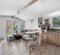 Interior of a cabin with wood-decor flooring, kitchen, and dining area.