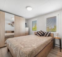 A bedroom in a cabin, with a bed, a wardrobe, and a floor with a wooden decor.