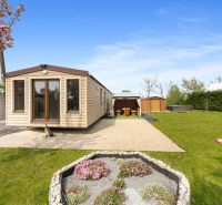 A cottage in Hurbanovo with a blooming garden, a gazebo, and a gravel path.