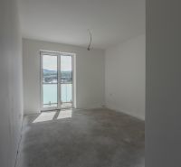 A room in a 2-room apartment with a large window without flooring with a wooden decor.