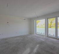 Empty room in a 2-room apartment with large windows and a view of the garden.