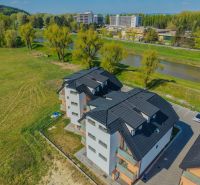 Apartment building with a black roof by the river on Moravanská Street in Banka.