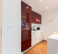A kitchen in a 2-room apartment with white cabinets and a wooden decor floor.