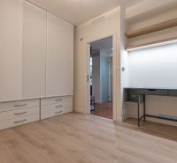 A bright room with a desk, a built-in wardrobe, and a wooden decor floor in a 2-room apartment.