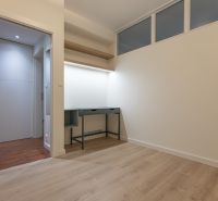 Empty room with wood-patterned flooring and a built-in desk in a two-room apartment.